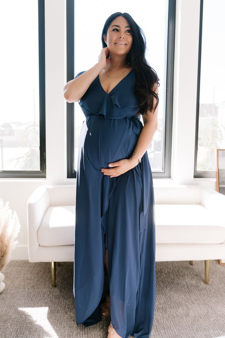 a woman standing in front of a window wearing a blue dress