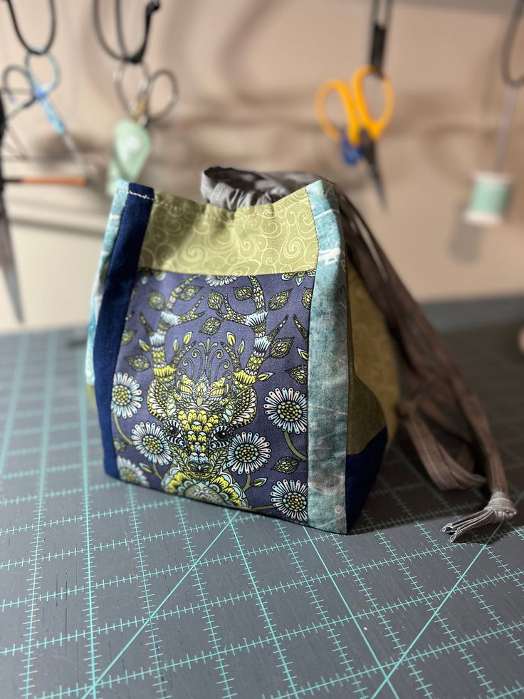 a small purse sitting on top of a cutting board next to scissors and other crafting supplies