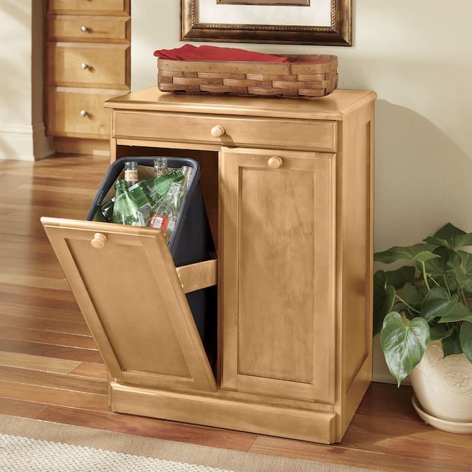 a wooden cabinet with two trash cans in it and a framed picture on the wall