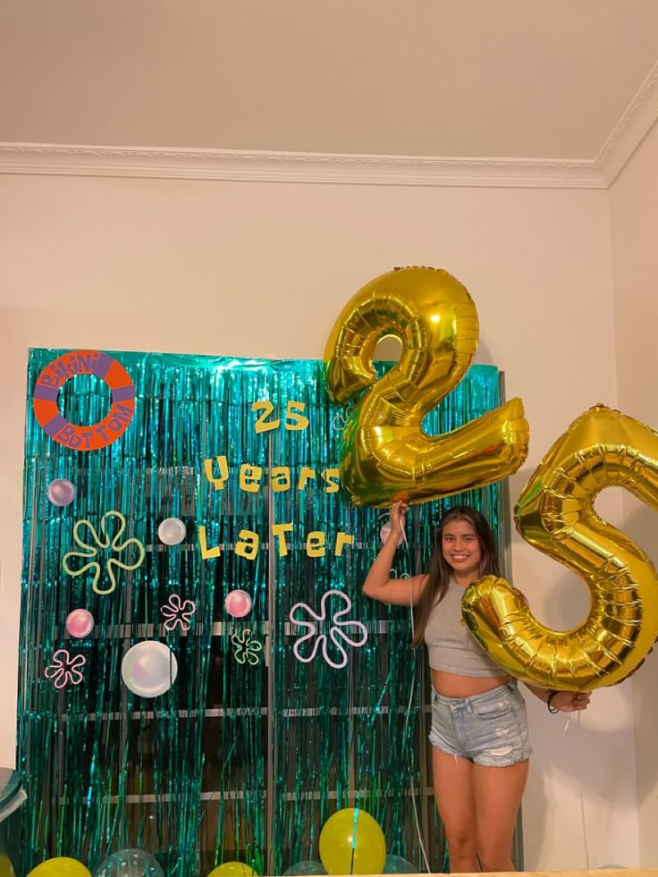 a woman holding up some balloons in front of a sign