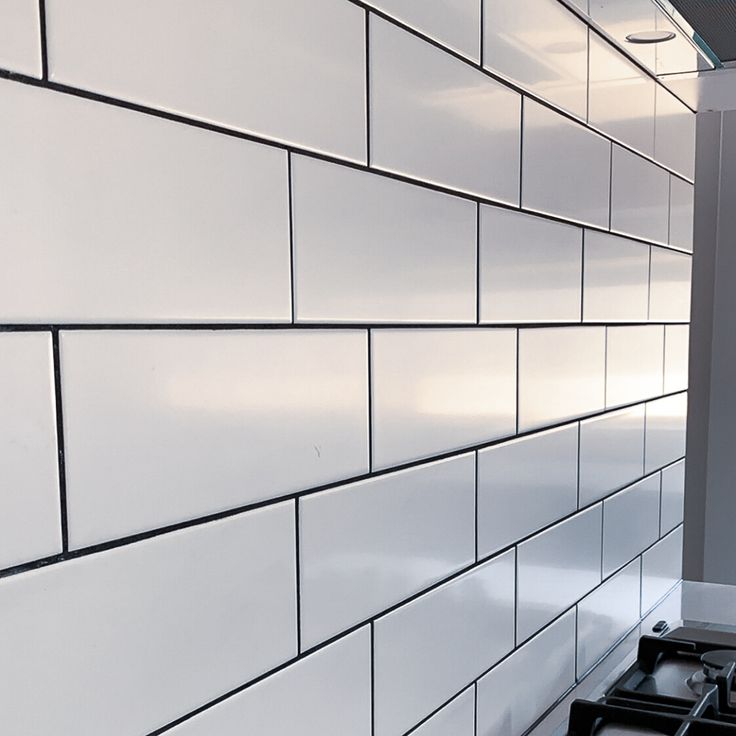 a stove top oven sitting next to a white tiled wall