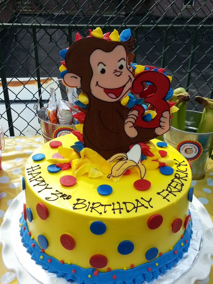 a yellow birthday cake with a monkey on top