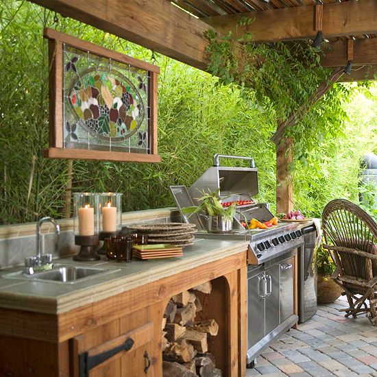 an outdoor kitchen with grill, sink and table set up for two people to eat