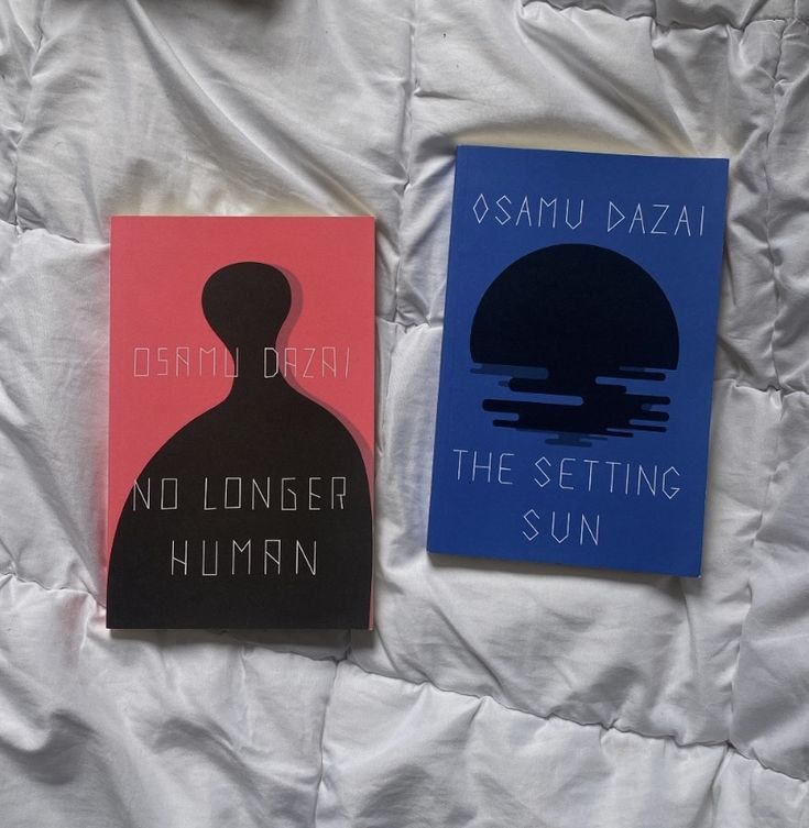 two books sitting on top of a bed next to each other in front of a white sheet