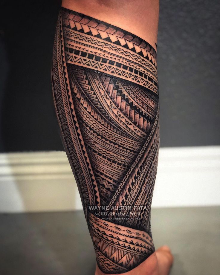 a man's leg with black and grey tattoos on it, showing the intricate design