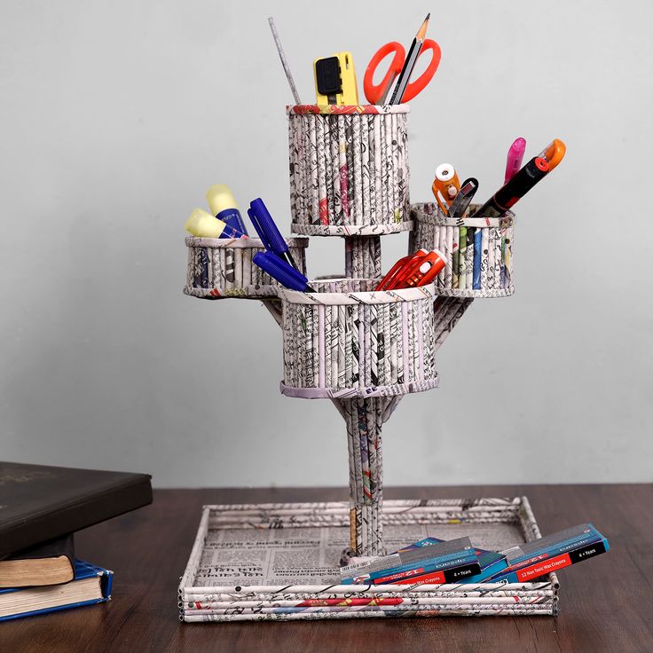 a stack of pens, scissors and other office supplies sits on a table next to an open book