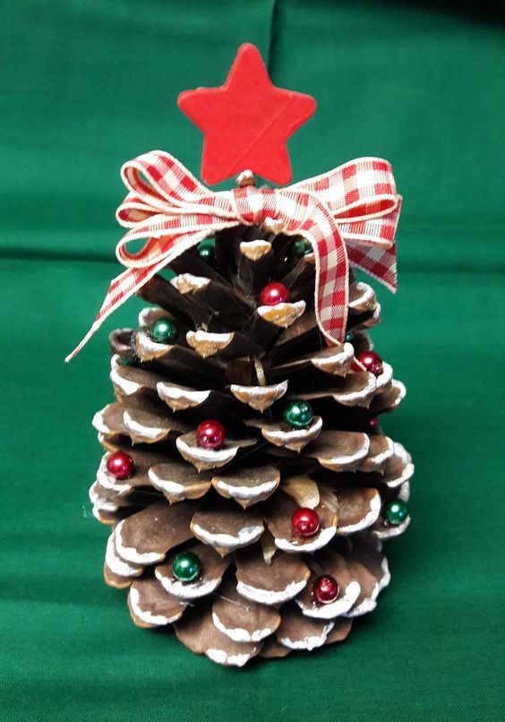 a pine cone with a red star on top is sitting in front of green fabric