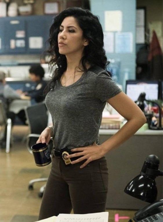 a woman standing in an office with her hands on her hips and holding a coffee mug