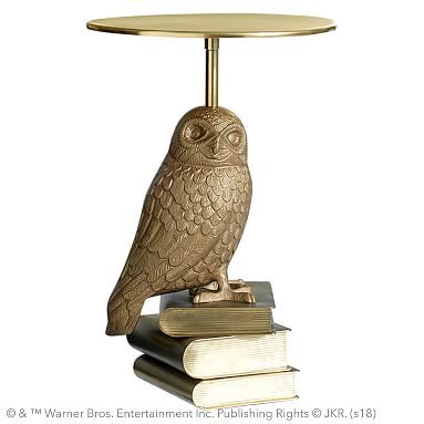 an owl figurine sitting on top of a stack of books next to a table