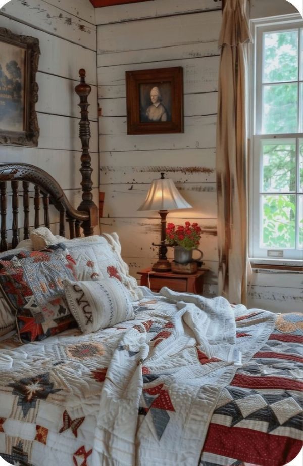 a bed with quilts and pillows in a bedroom next to a window on the wall