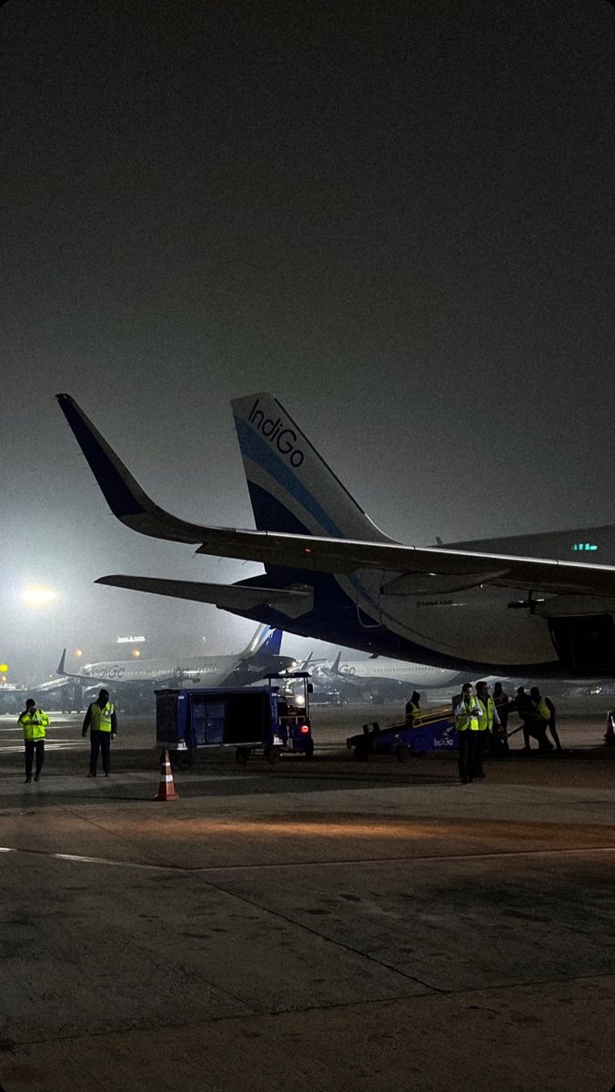 an airplane is parked on the tarmac at night with other planes in the background