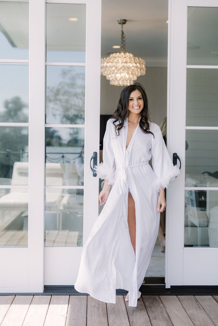 a woman standing in front of a door wearing a white robe and high heeled sandals