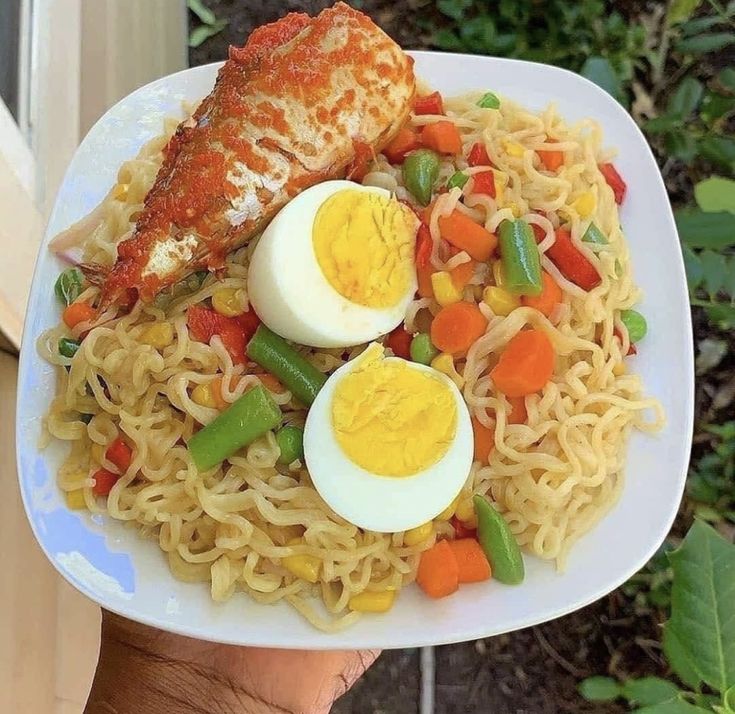 a white plate topped with noodles and meat next to an egg on top of it