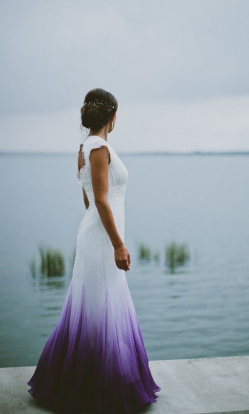 a woman in a white and purple dress looking out at the water