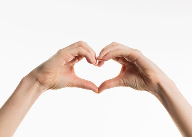 two hands making a heart shape with their fingers against a white background in front of the camera