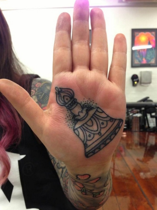 a hand with a bell tattoo on it