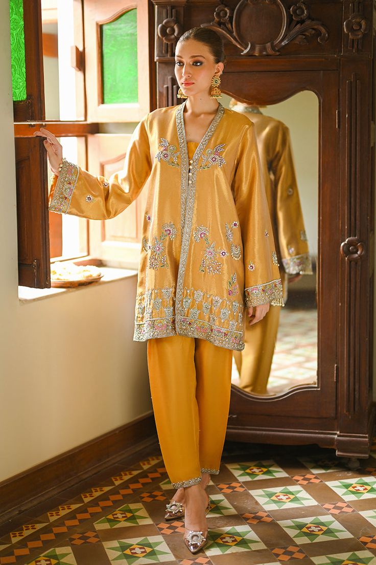 A tissue jacket in a shimmering shade of bronze crafted with zardoze work. Style it with a matching rawsilk shalwar and it can be the ideal choice for a classy evening soirée. Elegant Gold Chanderi Sherwani, Gold Raw Silk Dupatta With Naqshi Embroidery, Gold Raw Silk Dupatta With Naqshi Detail, Gold Naqshi Raw Silk Dupatta, Gold Hand-embellished Party Sets, Elegant Raw Silk Kurta With Dabka, Elegant Raw Silk Kurta With Dabka Details, Elegant Set With Zari Work And Front Open Shape, Gold Silk Dupatta With Naqshi