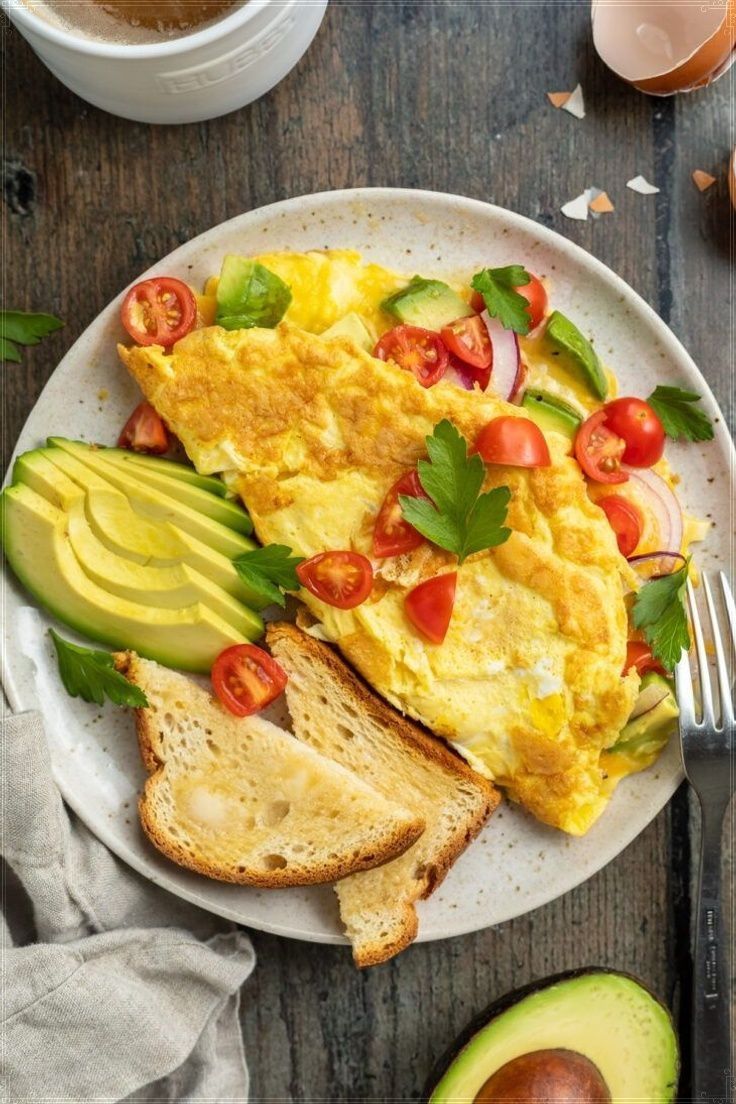 an omelet with tomatoes, lettuce and sliced avocado on a plate