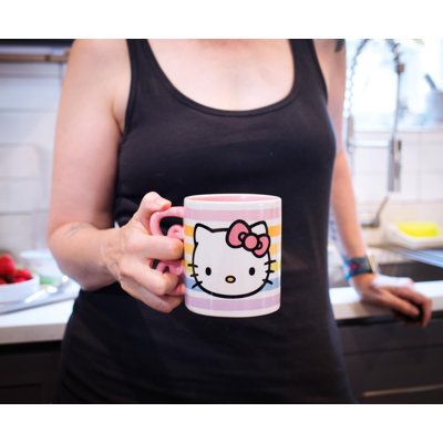 a woman holding a hello kitty coffee mug