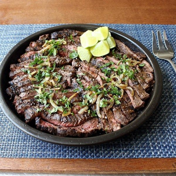 a bowl filled with meat and vegetables on top of a table next to a fork