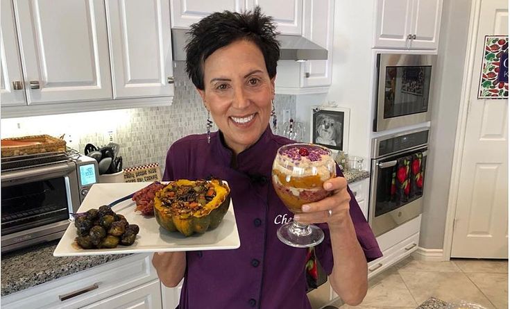 a woman holding a plate with food on it and a glass in front of her