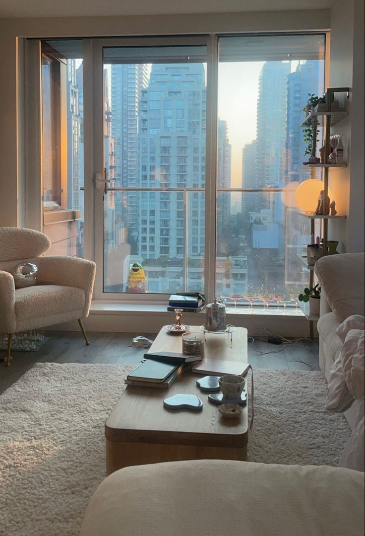 a living room filled with furniture and a large window overlooking a cityscape in the distance