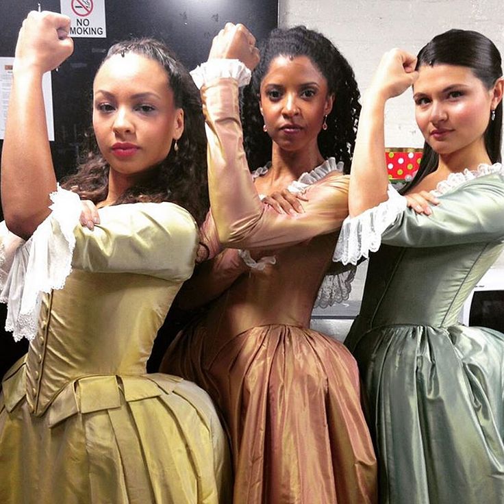 three women in dresses are posing for the camera with their arms up and one woman has her hand on her head