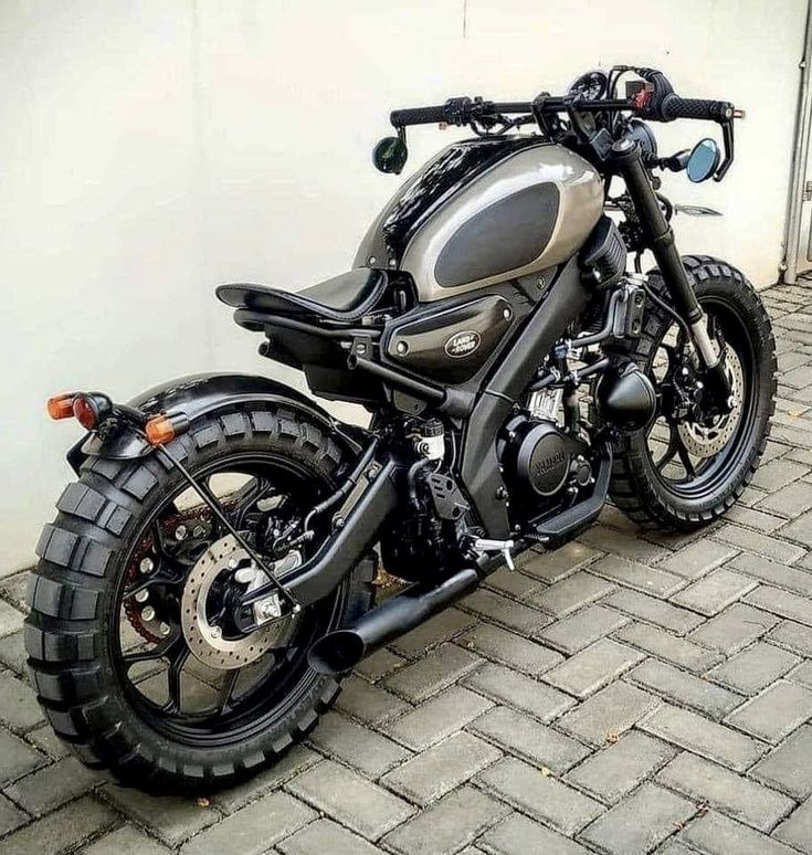 a motorcycle parked on the side of a road next to a white wall and fence