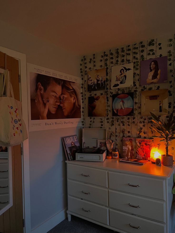 there is a dresser with many pictures on the wall and a lamp in front of it