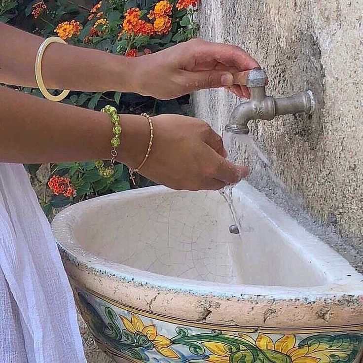 a woman is washing her hands with water from a faucet in a bowl