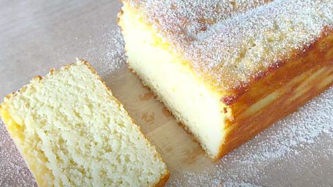 a piece of cake sitting on top of a wooden cutting board with powdered sugar