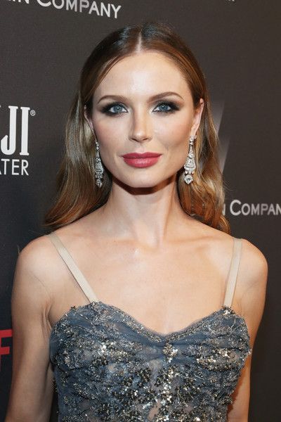 a beautiful woman in a strapless dress posing for the camera at an event with her hand on her hip