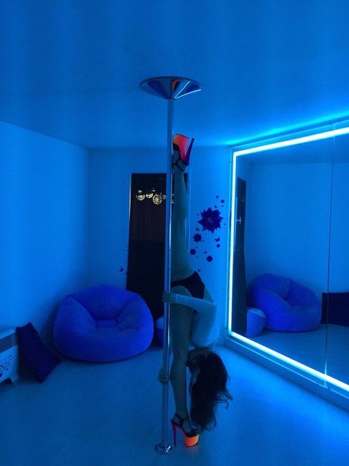 a woman is standing on a pole in the middle of a room with blue lights