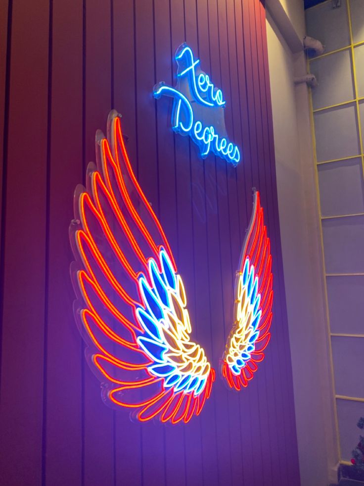 neon signs on the side of a building that says zone depreezo with wings