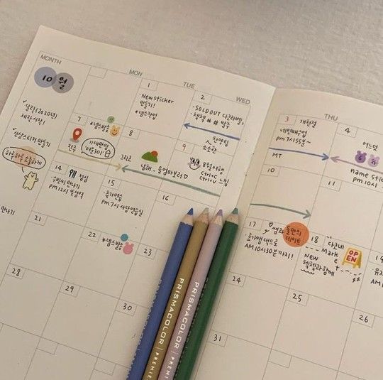 two pencils are sitting on top of a calendar with different things drawn on it