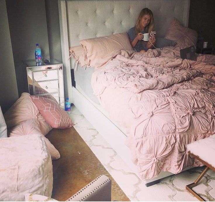 a woman is sitting on her bed drinking coffee