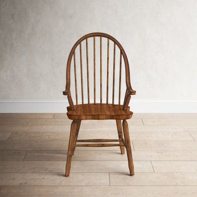 a wooden chair sitting on top of a hard wood floor next to a white wall