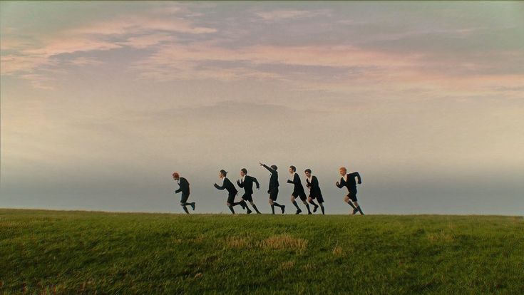 a group of people running across a lush green field