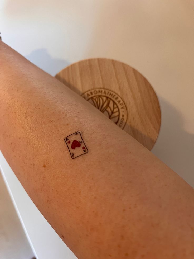 a woman's arm with a tattoo on it that has a playing card in the middle