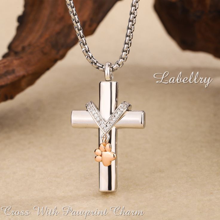 1. Serene Holy Cross Pendant: Our Cremation Necklace With Pawprint Charm features a sterling silver cross pendant of stunning elegance, crafted meticulously to honor your cherished pet's memory. This graceful design embodies sacred symbolism and is a treasured keepsake for pet lovers. Inspired by the enchanting bond we share with our beloved pets, the Memorial Necklace with Enchanted Pawprints is a sacred emblem of remembrance and affection, providing comfort during the grieving process. 2. Gold Elegant Memorial Cross Jewelry, Elegant Cross Pendant Jewelry For Memorial, Elegant Cross Jewelry For Memorial, Sterling Silver Cross Jewelry For Memorials, Spiritual Sterling Silver Cross Necklace For Anniversary, Elegant Cross Necklace For Memorial, Personalized White Cross Necklace, Engraved Cross Jewelry For Mother's Day, Elegant Memorial Cross Pendant Necklace