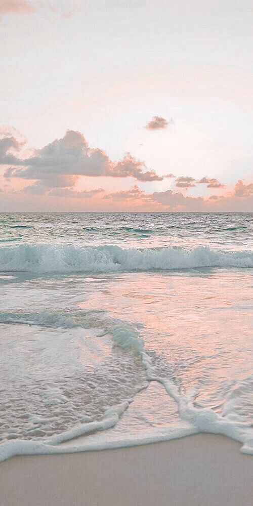 an ocean beach with waves crashing on the sand and clouds in the sky at sunset