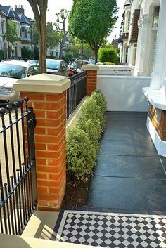 a black and white checkered floor next to a brick wall with an iron gate