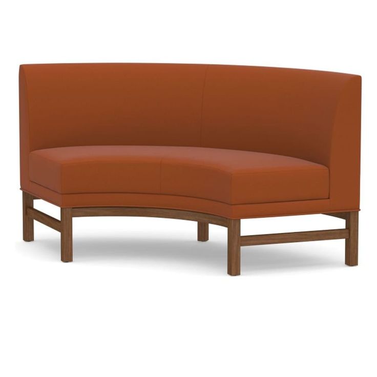 an orange curved couch sitting on top of a white floor next to a wooden frame