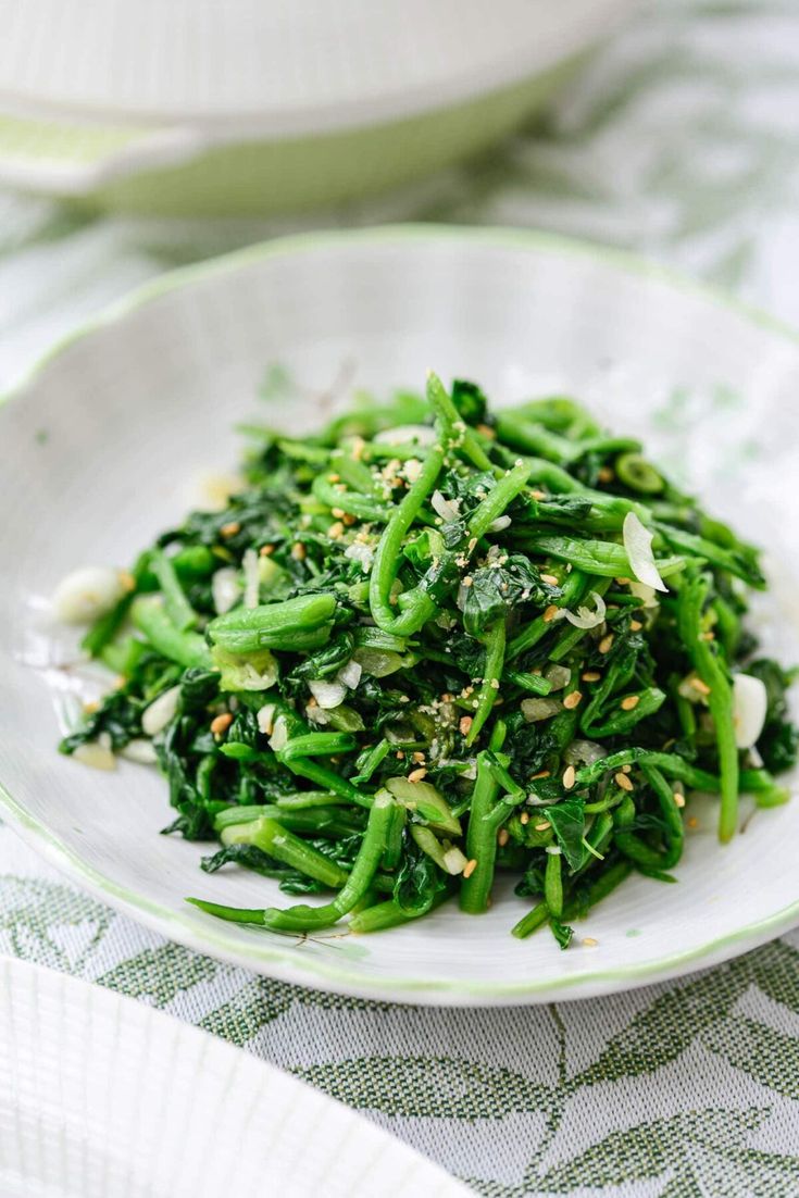 a white plate topped with green vegetables on top of a tablecloth covered table cloth