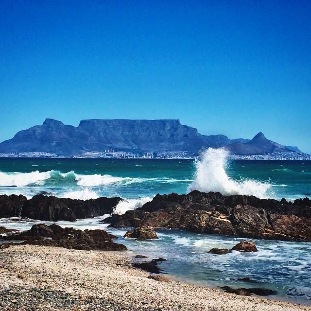 waves crashing on the rocky shore with mountains in the background