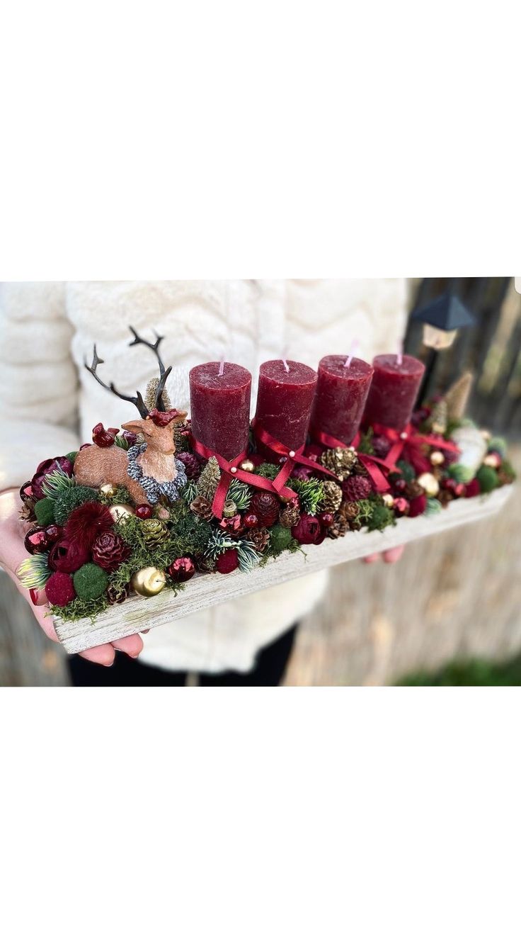 a person holding a tray with candles and christmas decorations