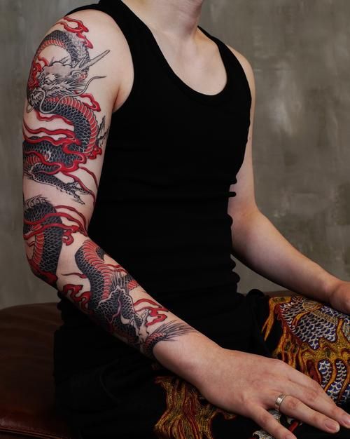 a man with tattoos on his arm sitting down