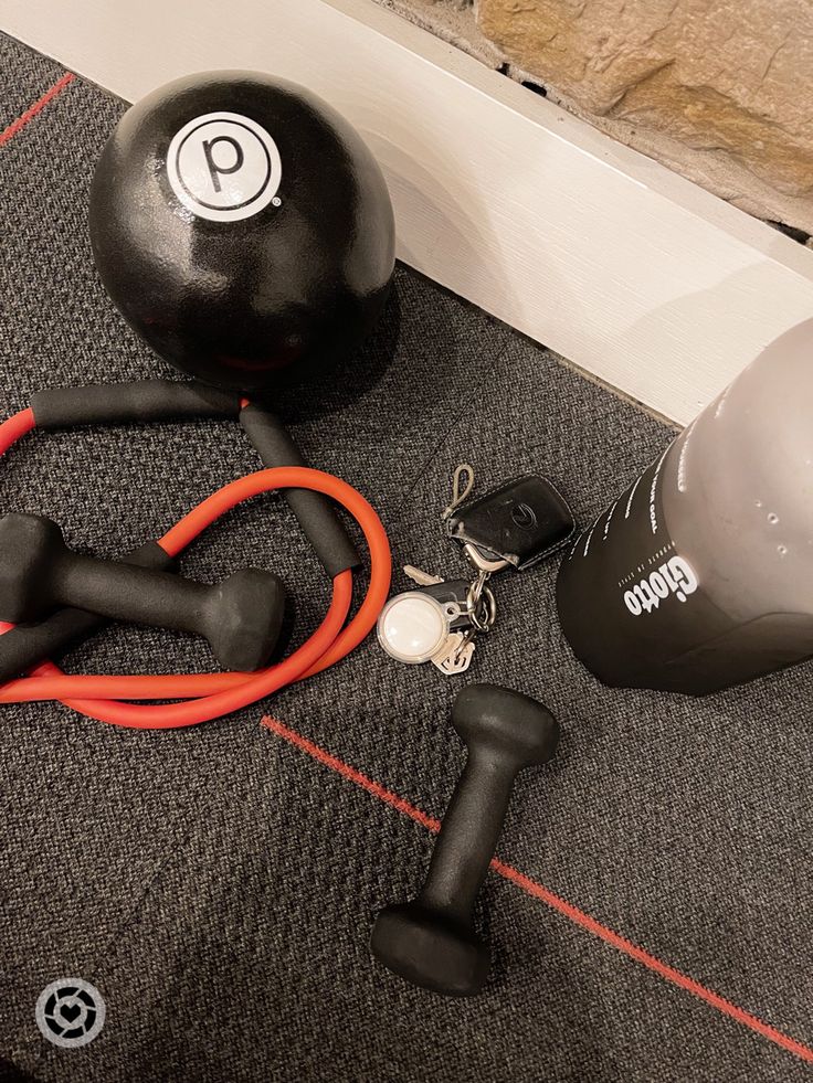 an exercise ball, skipping rope and earphones on the floor next to a wall