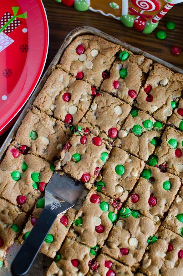 a pan filled with cookies and candy on top of a wooden table next to a red plate