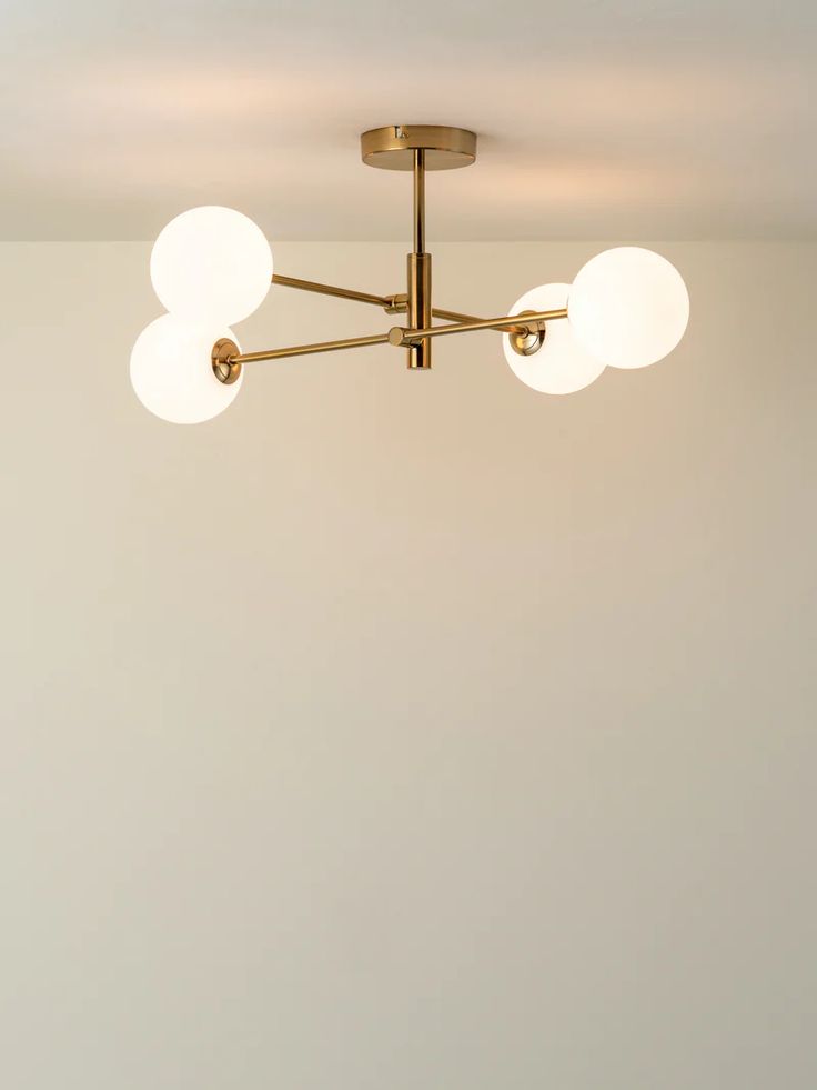 a ceiling light with three white balls hanging from it's center point in a room